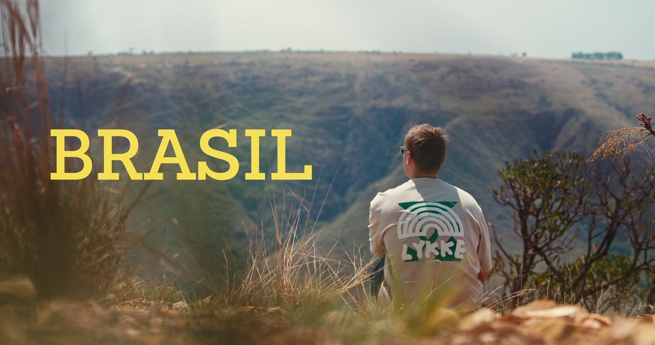 Title card of Klimatkaffe: BRASIL, a man in a Lykke shirt overlooking a valley.