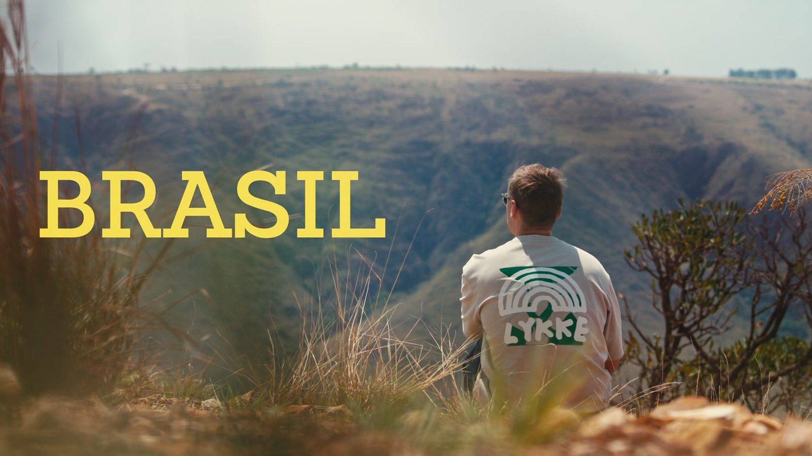 Title card from one of Lykke’s films from Brazil: a man in a Lykke shirt looks out over a valley.