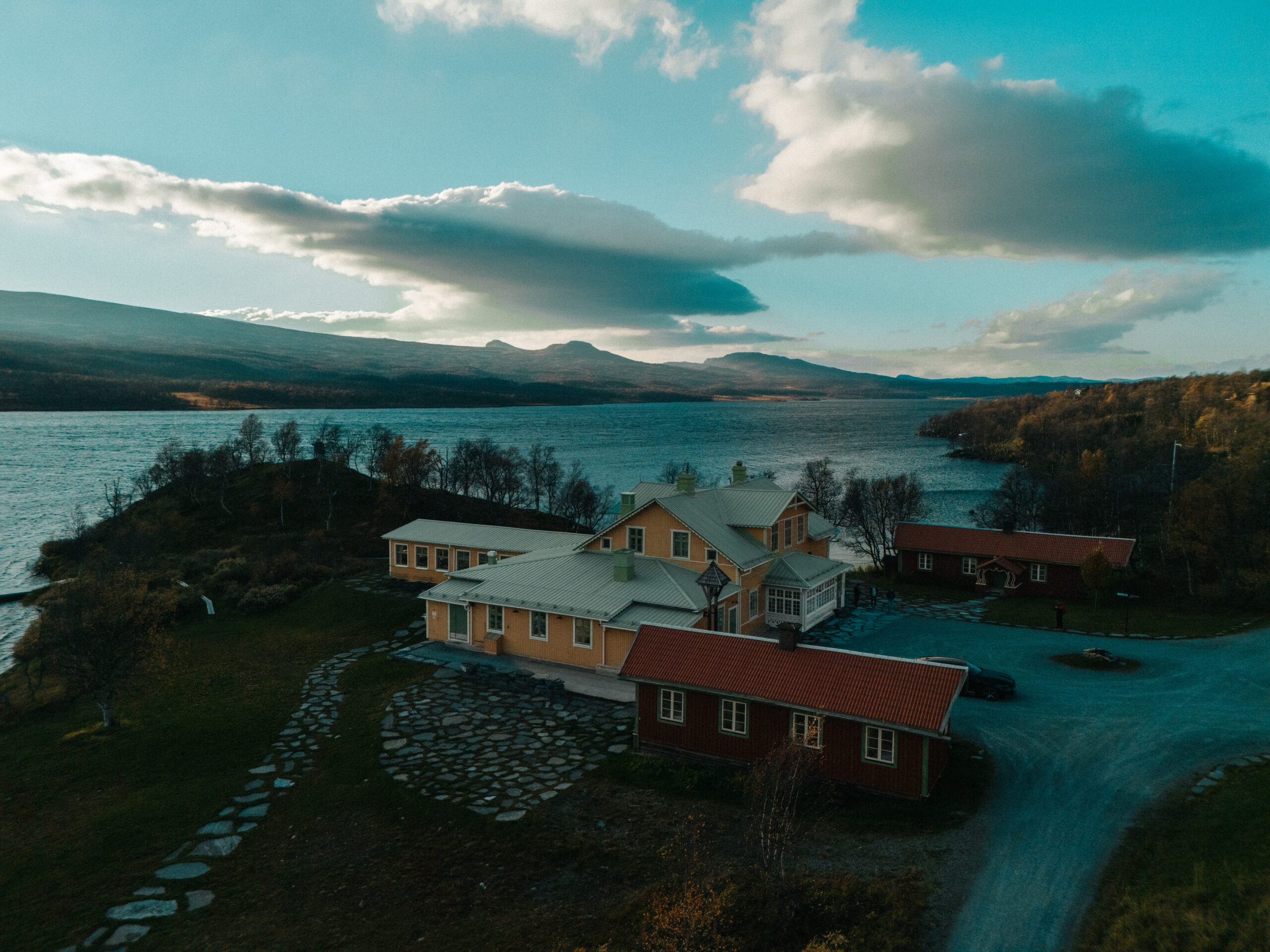 Fjällnäs from the air in autumn: the hotel buildings on a point by the lake, with the mountains behind.